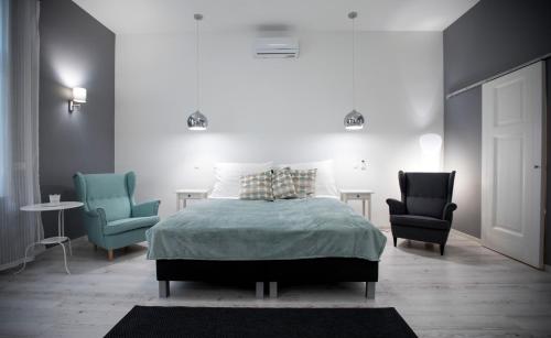 1 dormitorio con 1 cama y 2 sillas en City Center Stúdió Apartmanok en Szeged