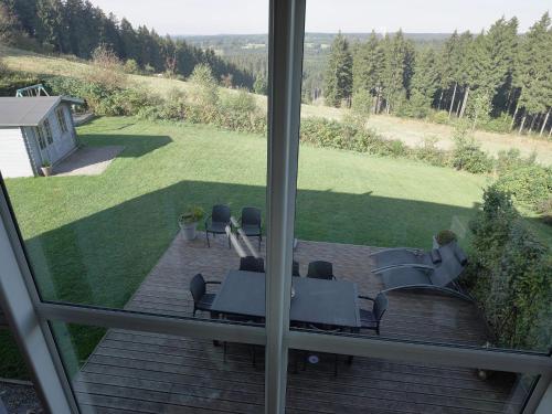 - une vue depuis la fenêtre d'une terrasse avec des tables et des chaises dans l'établissement Wonderful Holiday Home in Ovifat with Sauna, à Ovifat