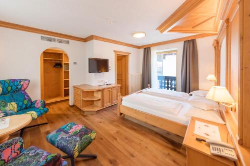 a bedroom with a large bed and a tv at Hotel Schlosswirt in Schenna