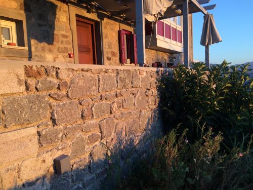 a house with a brick wall and an umbrella at Heliades Maisonettes in Mithymna