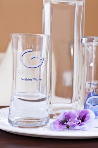 two glass vases and a flower on a plate at Engelhard Das Landhotel Garni in Kirchheim am Ries