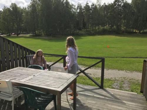 two girls standing on a deck with a table at Hällestrand Seaview Apartment in Strömstad