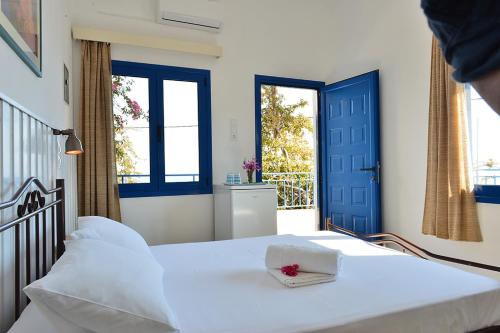 um quarto com uma cama branca e uma porta azul em Hotel Hariklia em Agia Galini