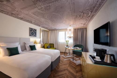 Pokój hotelowy z 2 łóżkami i biurkiem w obiekcie Mgallery Le Louis Versailles Château w Wersalu