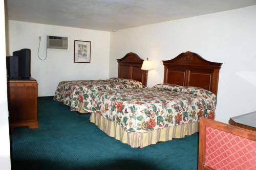 a hotel room with two beds and a television at HWY Express Inn and Suites in Thatcher