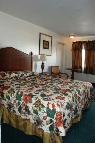 a bedroom with a bed with a floral bedspread at HWY Express Inn and Suites in Thatcher