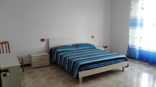 a bedroom with a bed with a blue and white striped blanket at Estia in Salemi
