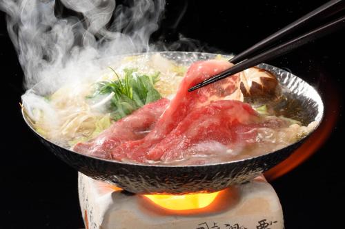 a bowl of soup with meat and vegetables in smoke at Kansyokan in Mogami