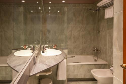 a bathroom with two sinks and a bath tub at Hotel Vetusta in Oviedo