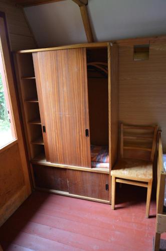a wooden cabinet with a chair in a room at Ubytování - U nás doma in Orličky