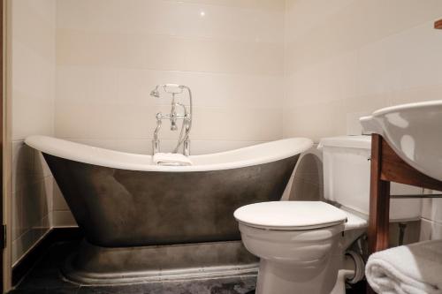 a bathroom with a tub and a toilet and a sink at Wykeham Arms in Winchester