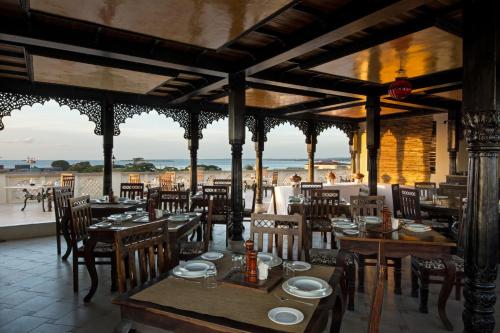a restaurant with tables and chairs and a view of the ocean at Golden Tulip Stone Town Boutique in Zanzibar City