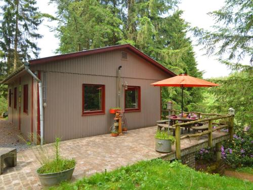 ein kleiner Schuppen mit einem Tisch und einem Regenschirm in der Unterkunft Chalet in a green and peaceful environment in Houffalize