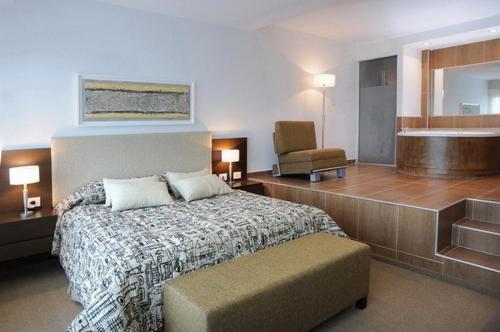 Lake Buenavista Apart Hotel & Suites في فيلا كارلوس باز: غرفة نوم بسرير وكرسي وحوض استحمام