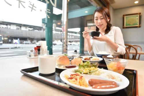 a woman sitting at a table with a tray of food at Hotel Seawave Beppu in Beppu