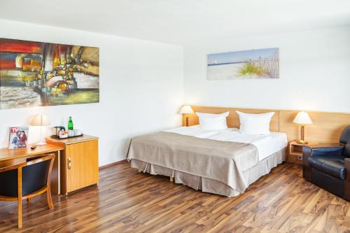 a bedroom with a bed and a desk and a chair at Hotel Plöner See by Tulip Inn in Plön