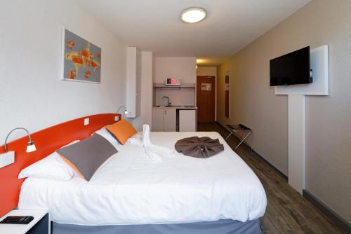 - une chambre avec un grand lit blanc et une tête de lit orange dans l'établissement City Résidence Strasbourg Centre, à Strasbourg