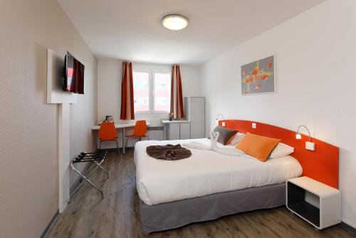 - une chambre avec un grand lit et une tête de lit orange dans l'établissement City Résidence Strasbourg Centre, à Strasbourg