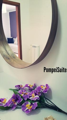 a mirror and purple flowers on a table in a room at Pompei Suite in Pompei