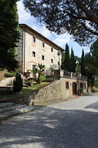 a large stone building with a stone wall next to a street at Villaggio Albergo San Lorenzo e Santa Caterina in Pescia