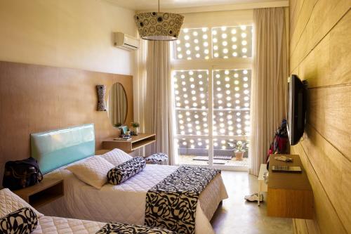 a hotel room with two beds and a window at Hotel Resort e Golfe Clube dos 500 in Guaratinguetá