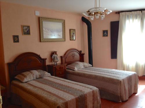 una camera con due letti e un lampadario a braccio di Encanto de Aragón a Torres de Albarracín