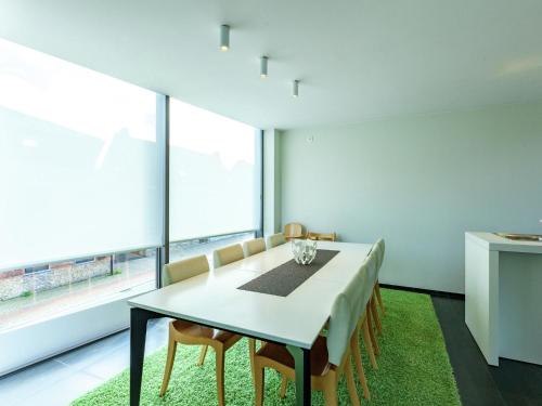ein Esszimmer mit einem Tisch, Stühlen und Fenstern in der Unterkunft Modern holiday home near Bruges and the North Sea in Dudzele