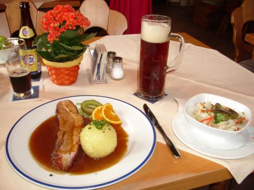 uma mesa com um prato de comida e um copo de cerveja em Komforthotel Ahornhof em Lindberg