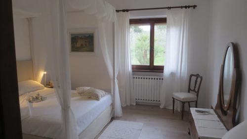 a white bedroom with a bed and a window at B&B Casa Soresina in Offagna