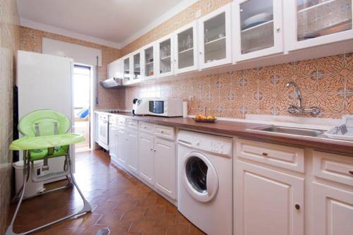 a kitchen with a washing machine and a green chair at Em frente à Praia e Marina in Vila do Conde