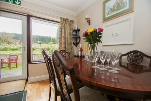 a dining room with a wooden table with wine glasses at Dean Court Bungalow - Parking - by Brighton Holiday Lets in Rottingdean