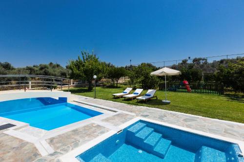 a swimming pool in a yard with two lounge chairs at Villa Mary in Pigi