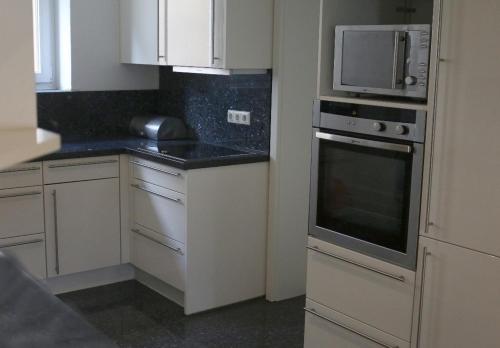 a kitchen with white cabinets and a microwave at Ferienwohnung Amperblick Fürstenfeldbruck in Fürstenfeldbruck