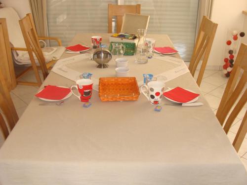 een witte tafel met rode servetten en borden erop bij Chambres d'hôtes Sébastien in Ruaudin