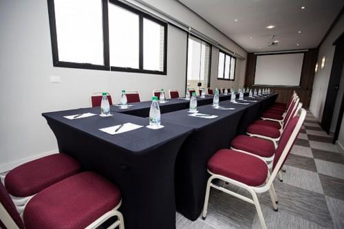 a conference room with a long table and red chairs at Rio Hotel by Bourbon Curitiba in Curitiba