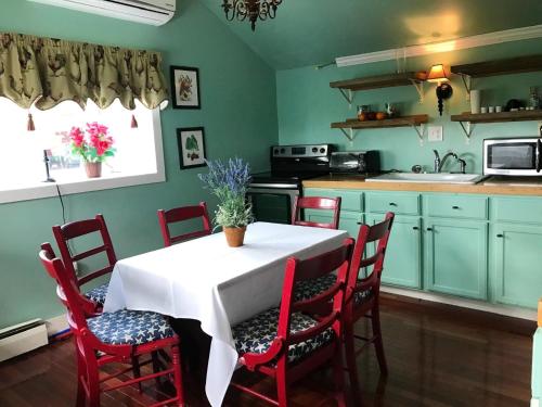 una cocina con mesa con sillas y una cocina con armarios verdes en John Joseph Inn, en Groton