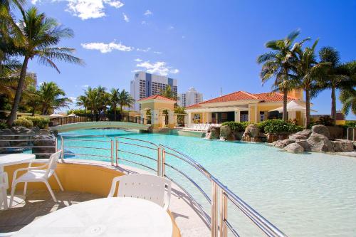 
a beach scene with a large building and palm trees at Mantra Towers of Chevron in Gold Coast
