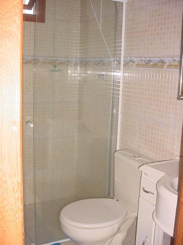 La salle de bains est pourvue de toilettes et d'une douche en verre. dans l'établissement Tranquilidade na Praia da Gamboa, à Garopaba