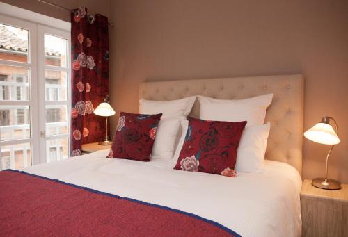 a bedroom with a white bed with red pillows at L'appart du Cloitre in Albi