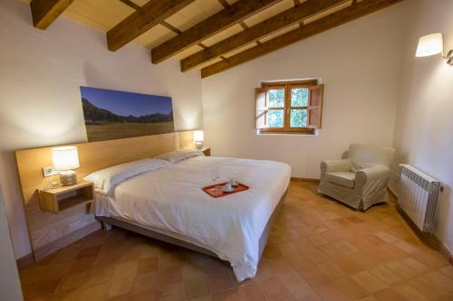 a bedroom with a large white bed and a chair at Agroturismo Son Alzines in Lluc
