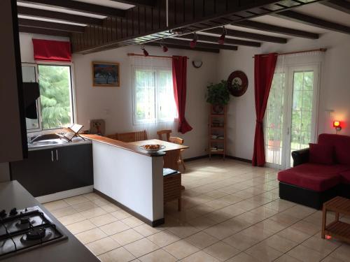 uma cozinha e sala de estar com um sofá vermelho em Meublé de tourisme "Au bord de la Mare" em Salazie