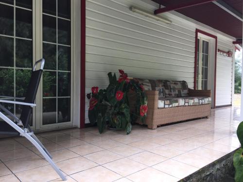 a porch with a couch on the side of a house at Meublé de tourisme "Au bord de la Mare" in Salazie
