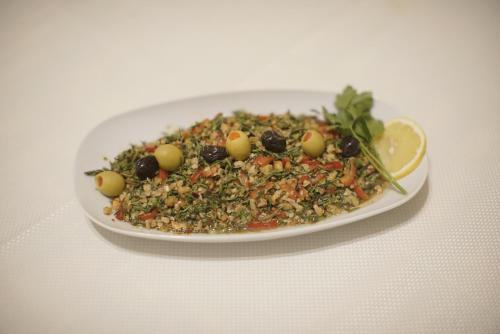 a plate of salad with olives and a lemon at Yoruk Stone House in Nevsehir
