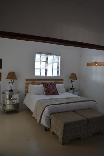 a bedroom with a large bed with two tables and a window at Gecko Cottages in Prince Albert