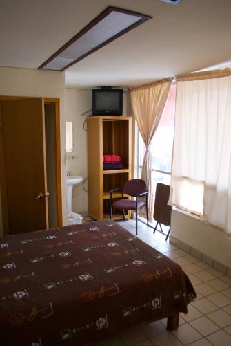 Cette chambre comprend un lit, un bureau et une fenêtre. dans l'établissement Hotel Centric Chihuahua, à Chihuahua