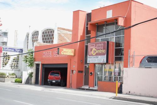 Hotel Centric Chihuahua في تشيواوا: مبنى احمر على زاوية شارع به كراج سيارات