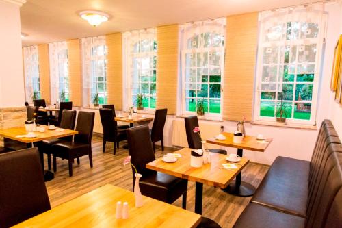 Un restaurante con mesas y sillas de madera y ventanas. en Parkhotel Altenburg, en Altemburgo