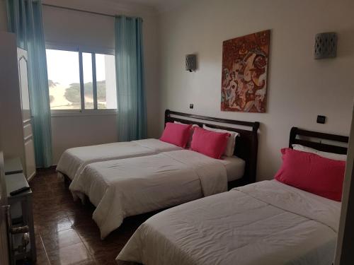 1 dormitorio con 2 camas y almohadas rosas en Issablanca, en Oualidia