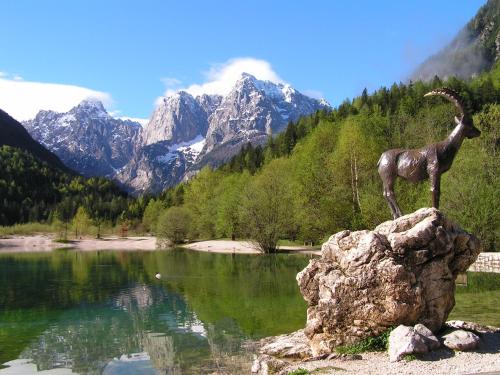 a statue of a goat on a rock next to a lake at TEMPFER 2 Apartments & Rooms with new WELLNESS in Kranjska Gora