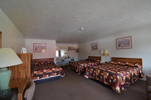 a hotel room with three beds in a room at Dude & Roundup in West Yellowstone